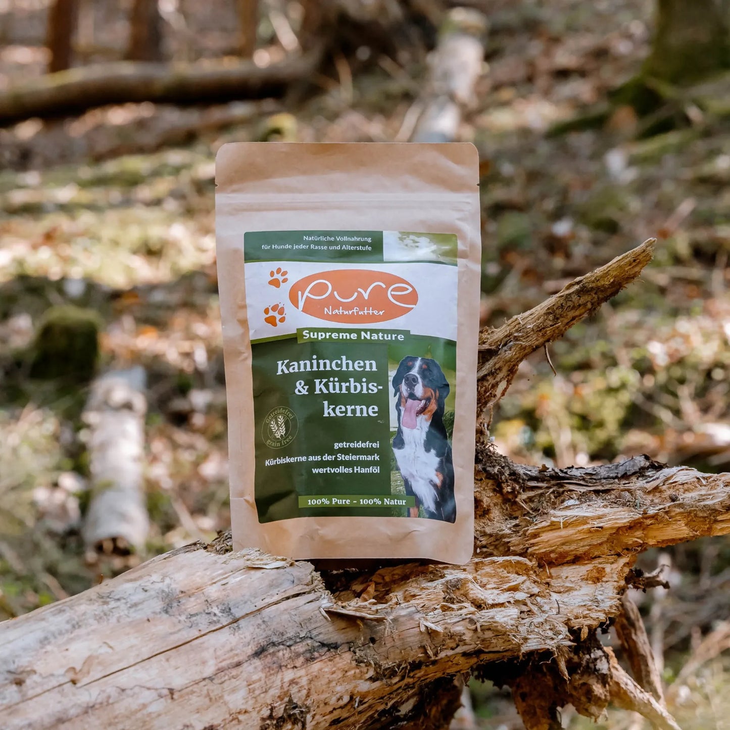Beutel PURE Kaninchen & Kürbiskerne steht im Wald auf einem Baumstamm – getreidefreies Trockenfutter für Hunde
