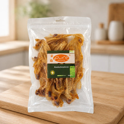 PURE Naturfutter Kaninchenohren 200 g als natürlicher Kausnack für Hunde auf Holzuntergrund
