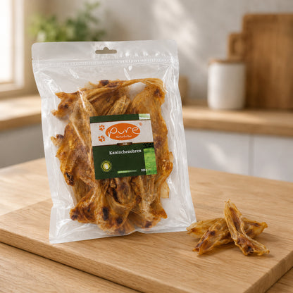 Getrocknete Kaninchenohren von PURE Naturfutter im Beutel und lose daneben als natürlicher Hunde-Kausnack
